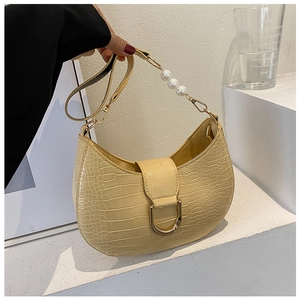 Macro view of beige crocodile embossed texture handbag with pearl strap and metal D-ring buckle