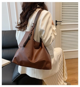 Detailed view of the large brown tote bag with wide strap and matching mini pouch