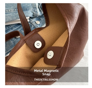 Close-up of metal magnetic buckle and pebble texture leather on brown tote bag