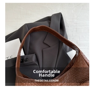 Close-up of the woven leather texture and sturdy handle connection of this brown tote bag