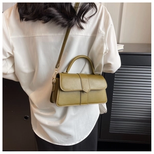 Olive green leather crossbody bag with top handle shown on a white shirt model
