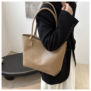 Close-up of the fine woven texture and soft leather shoulder strap on a khaki tote bag