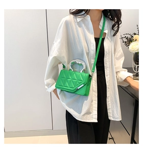 Detail of bright green quilted square bag with silver metal handle and shoulder strap