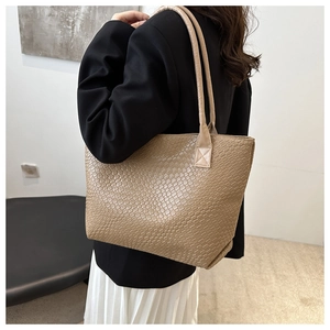 Detailed close-up of khaki woven texture tote bag worn over the shoulder by a model