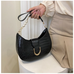 Detail of black crocodile texture crescent bag with pearl handle and gold hardware