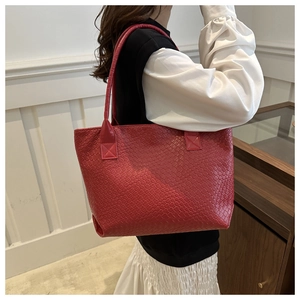 Detail of red woven leather tote bag showing large capacity and textured shoulder strap