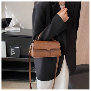 Detailed view of a vintage brown leather crossbody bag with metal buckle and slim strap