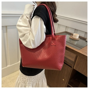 Detailed view of large red woven tote bag featuring textured cross-weave craft on side