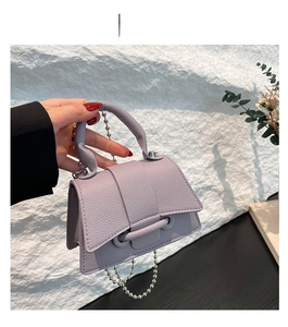Détail du mini sac violet en cuir grainé avec bandoulière chaîne et fermoir élégant