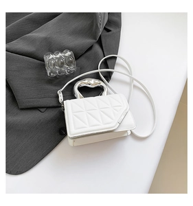 Detail of silver metallic curved handle and quilted geometric texture on a white handbag