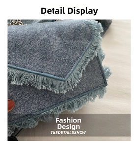 Close-up of washed blue denim crossbody bag with frayed edges and metal chain strap