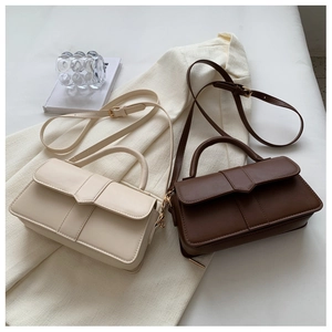 Detail view of cream and dark brown leather crossbody bags on a beige blazer