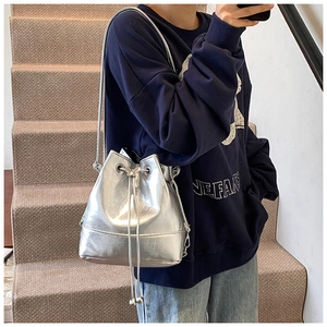 Detail of silver metallic bucket bag with drawstring closure and fine chain strap