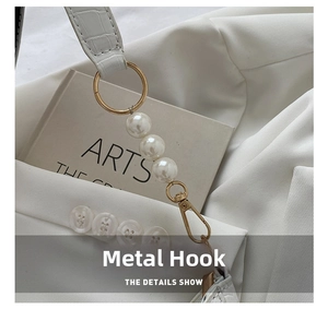 Detail of white crocodile texture strap with gold ring, pearls, and lobster clasp hardware