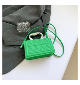Detail of green quilted crossbody bag featuring a unique silver fluid metal handle