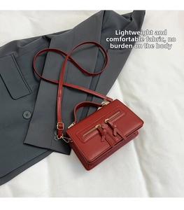 Close-up of a red rectangular handbag featuring dual metal zippers and leather knotted pulls