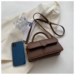 Detailed view of brown matte leather crossbody bag with top handle and gold hardware