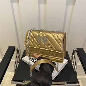 Sac à main doré matelassé avec boucle papillon argentée et bandoulière en chaîne