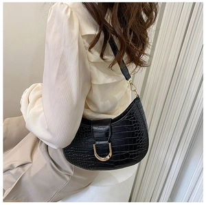 Detail of black crocodile texture hobo bag with gold hardware worn on shoulder