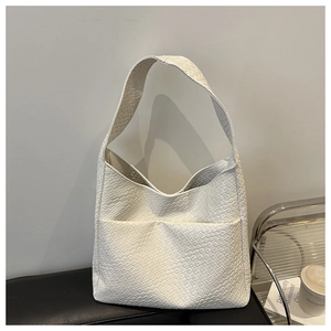 Detail of white woven tote bag with front pockets on a black leather chair