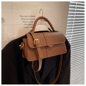 Detail of vintage brown crossbody bag with textured leather and metal buckle on suit