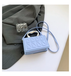 Close-up of light blue quilted handbag featuring silver heart-shaped metal handle