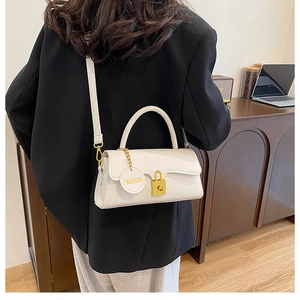 Detailed close-up of white rectangular crossbody bag with golden buckle and circular charm