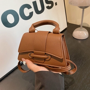 Brown litchi grain mini handbag with top handle and crossbody strap in modern home setting