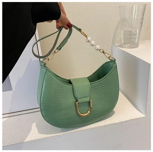 Detail of light green faux crocodile leather bag with gold buckle and pearl strap decor