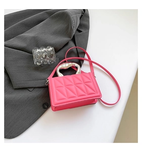 Macro detail of quilted neon pink PU leather mini handbag with stylish silver metal handle