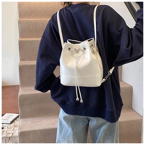 Detail of white PU leather bucket backpack featuring a silver butterfly drawstring buckle