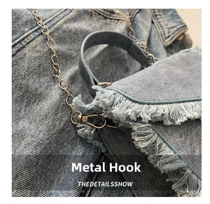 Detailed macro of silver metal hook and frayed denim edges on a light blue wash bag