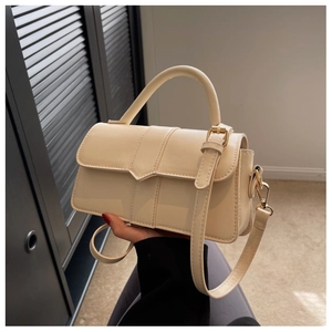 Close-up of cream rectangular handbag showing gold hardware and textured leather finish