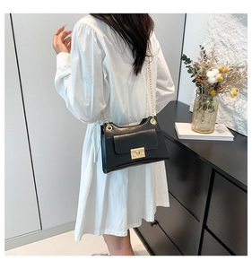Classic black leather square crossbody bag with gold chain strap worn by a model