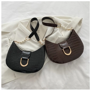 Detail of crocodile-embossed half-moon bags with gold D-buckles and pearl shoulder chains