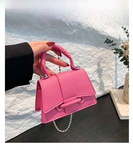 Détail du sac à main en cuir litchi rose fuchsia avec chaîne argentée et barre décorative