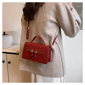 Fashionable red matte leather crossbody bag worn by model in an elegant interior setting