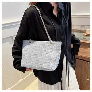 Détail du sac cabas en tweed bleu clair montrant la texture tissée et la chaîne dorée