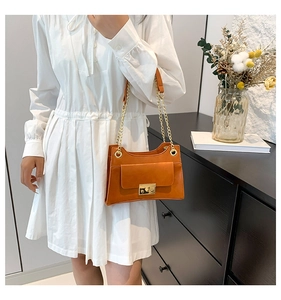 Detail of caramel faux leather bag with gold chain strap and elegant metal clasp