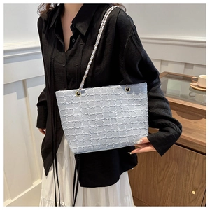 Détail du sac cabas en tweed bleu clair montrant la texture et la chaîne dorée