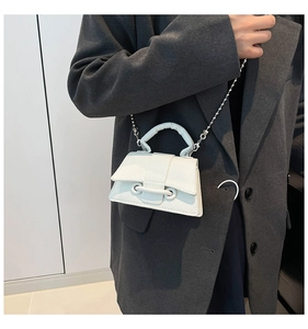 Mini sac bandoulière blanc en cuir grainé avec chaîne à boules porté par un modèle