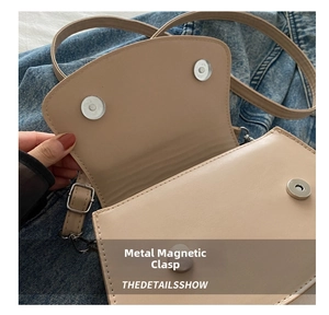 Detail of beige leather crossbody bag featuring secure double magnetic hardware buckles