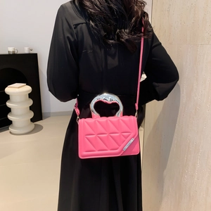 Pink quilted crossbody bag with unique silver metal handle on a model in lifestyle setting