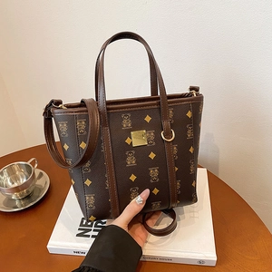 Sac seau vintage marron avec motif ours, doté de deux poignées et d'accessoires dorés