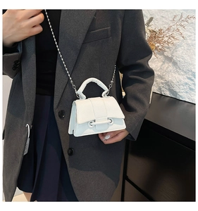 Mini sac blanc motif litchi avec chaîne perlée argentée porté sur un blazer foncé