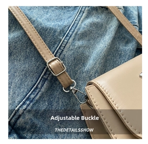 Detail of adjustable shoulder strap with silver metal buckle and hook on khaki bag