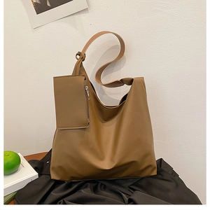 Detailed view of brown leather Hobo bag with a matching small zipper pouch on silk