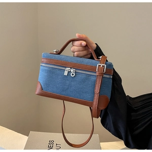 Detail of denim and brown leather patchwork handbag with adjustable shoulder strap