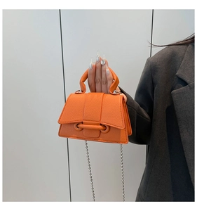 Détail du sac bandoulière orange en cuir grainé avec chaîne argentée et poignée