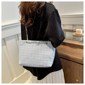 Détail du sac cabas en tweed clair avec texture de chaîne et tissu tissé chic